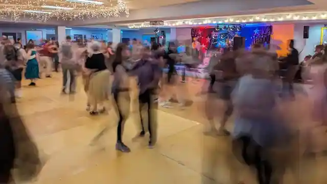 Dancers moving together across a warmly lit dance floor in a long-exposure photograph
